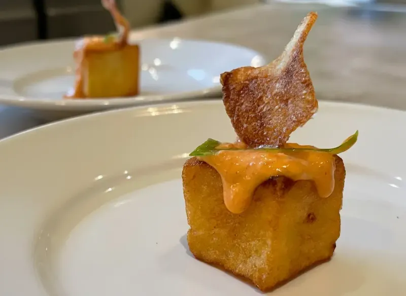 A plated brunch bite topped with crisp bacon